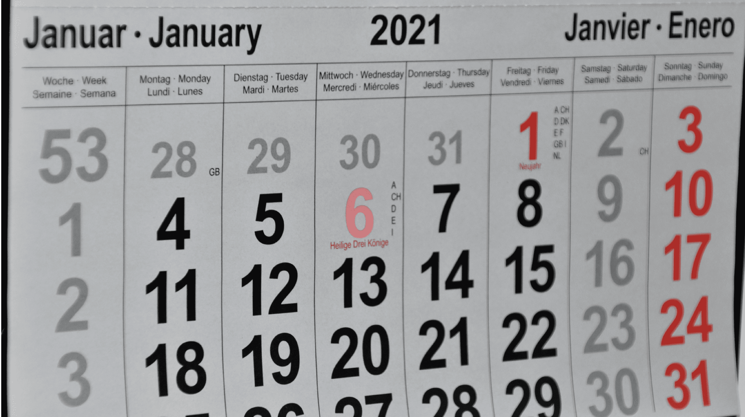 "Close-up of a custom printed wall calendar grid template showcasing January dates with clean black and red bold numbers and multilingual headings."